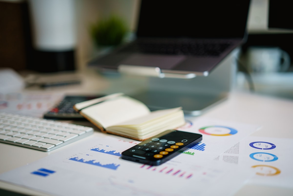 Desk with financial charts and a smartphone, representing productivity measurement data